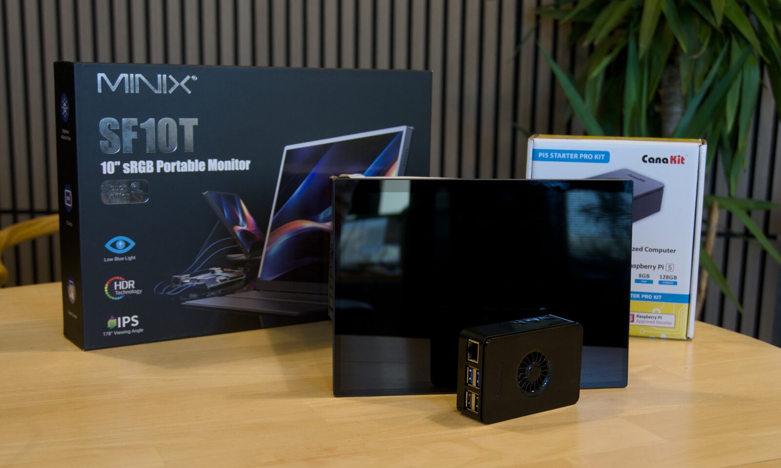 A Raspberry Pi 5 in a fan case beside a portable monitor and a starter kit — the hardware the build runs on.